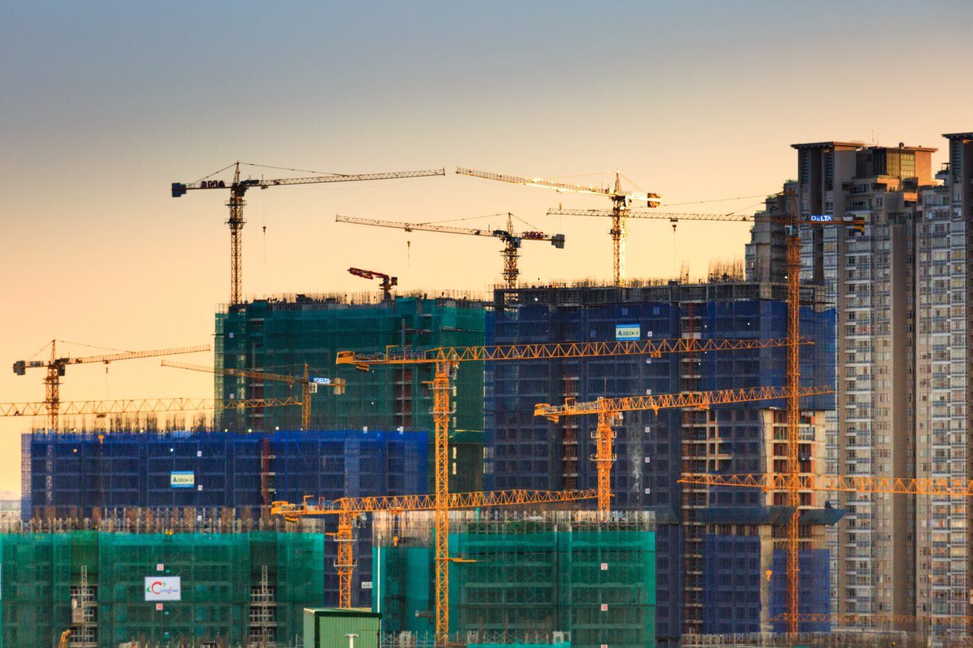 Cranes on a construction site at sunset.