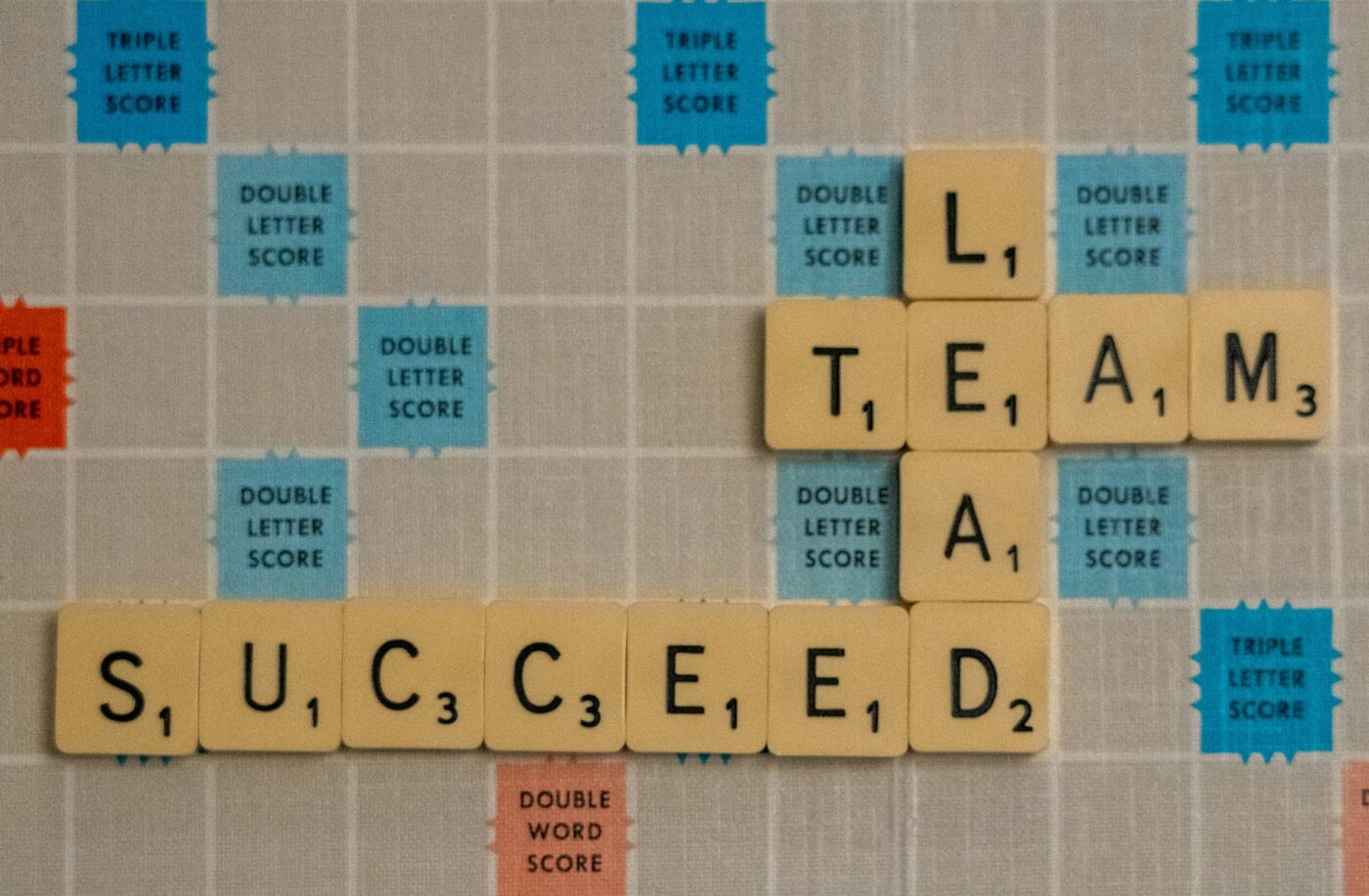scrabble board with the words lead, team succeed.